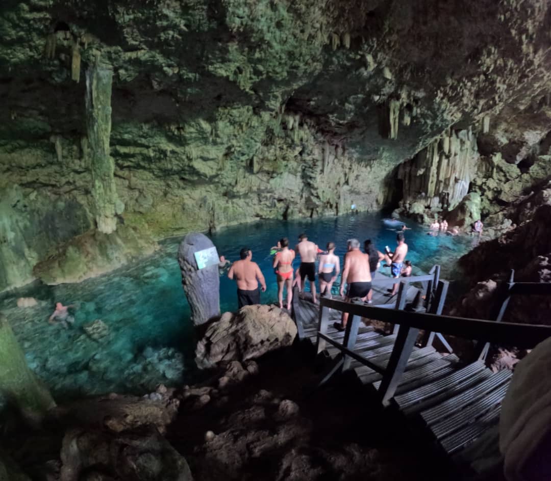 Snorkelers exploring the clear turquoise waters of Saturn Cave in Varadero, Cuba, surrounded by natural rock formations, stalactites, and stalagmites.